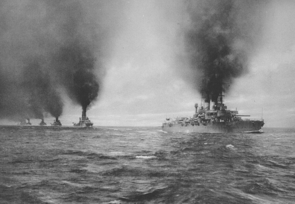 U.S. Navy ships belching black smoke from coal-fired boilers.