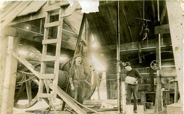 Old photo of nitro pouring as worker is preparing to "shoot" a well drilled by a cable-tool rig.