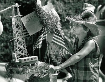 Woman pushes a cart with model derrick and American flags in this news photo.